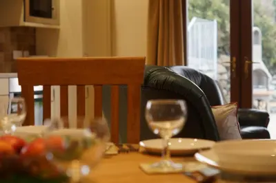 a dining room table with a glass of wine on it at Enlli Lodge in Llanddwywe