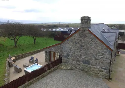 an external view of a stone house with a swimming pool at Hafod in Llanddwywe
