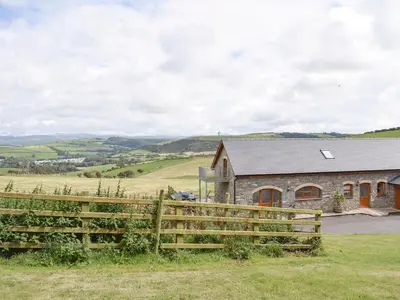 a barn with a fence in front of a house at No 1 Pegraig Draw - Uk6434 in Llanychaiarn