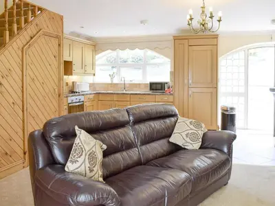 a leather couch in a living room with a kitchen at No 1 Pegraig Draw - Uk6434 in Llanychaiarn