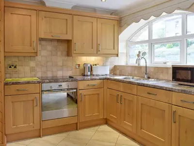 a kitchen with wooden cabinets and a sink and a window at No 1 Pegraig Draw - Uk6434 in Llanychaiarn