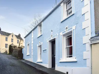 a blue building with white windows on a street at Delfryn in Llanarth
