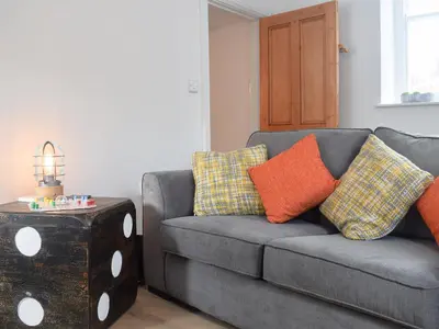 a living room with a gray couch with pillows and a table at Delfryn in Llanarth