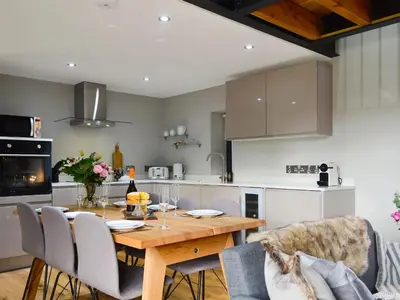 a kitchen and dining room with a wooden table and chairs at Maes Merlin in Llanddeusant