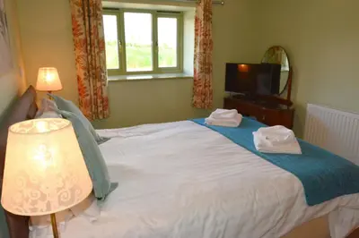 a bedroom with a bed and a window and a television at Upper Onibury Cottages in Onibury