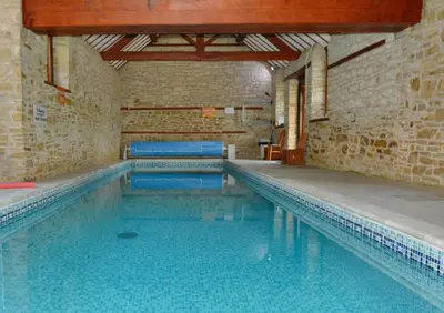 a large swimming pool in a brick building at Upper Onibury Cottages in Onibury