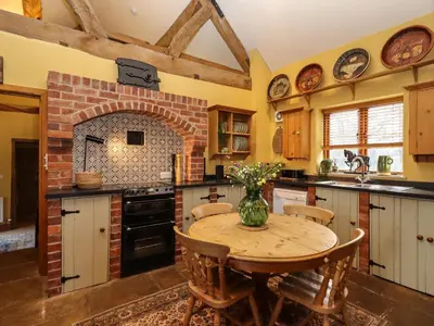 a kitchen with a wooden table and a brick fireplace at The Granary in Shrewsbury