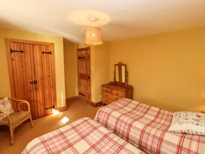a bedroom with two beds and a chair and a mirror at The Granary in Shrewsbury