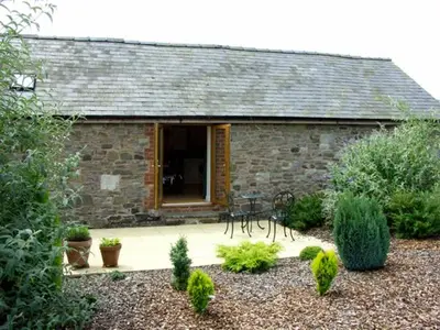 a stone house with a table and chairs in front of it at The Byre in Bishops Castle