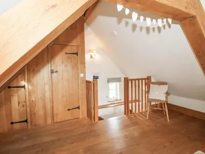 an attic room with a staircase and a chair at The Old Workshop in Church Pulverbatch