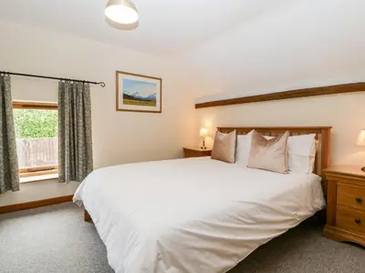 a bedroom with a large white bed and a window at Stable End in Pembridge