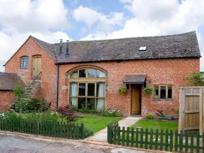 a brick house with a fence in front of it at The Coach House in Shrewsbury