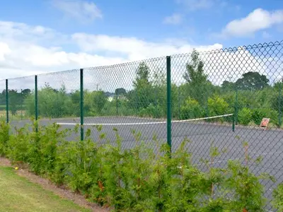 a tennis court behind a fence with a net at The Coach House in Shrewsbury