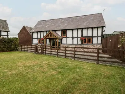 a white and black house with a wooden fence at The Hop Kiln in Pembridge