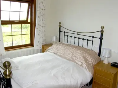a bedroom with a white bed and a window at Railway Cottage in Fairbourne