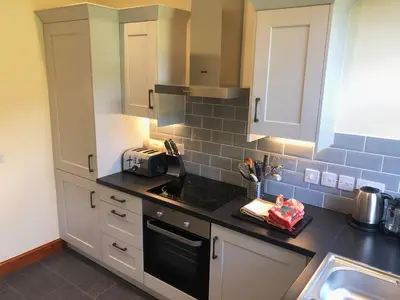 a kitchen with white cabinets and a black counter top at Railway Cottage in Fairbourne
