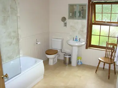 a bathroom with a tub and a toilet and a sink at Railway Cottage in Fairbourne