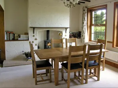 a dining room with a table and chairs and a fireplace at Railway Cottage in Fairbourne