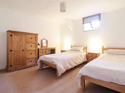 a bedroom with two beds and a dresser and a window at Y Bwthyn in Llanbedr