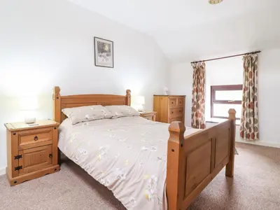 a bedroom with a wooden bed and two night stands at Y Bwthyn in Llanbedr
