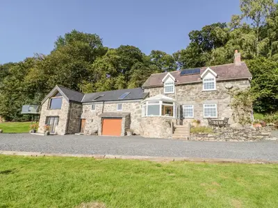 a large stone house with a driveway at Tyn Llwyn in Gwyddelwern