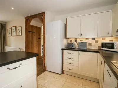 a kitchen with white cabinets and a white refrigerator at The Milking Parlour in Craven Arms