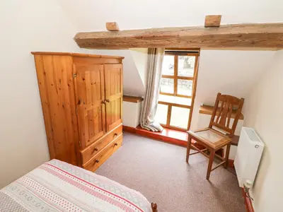 a bedroom with a bed and a chair and a window at The Stable in Craven Arms