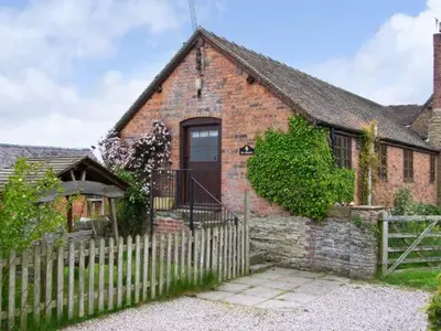 a brick house with a wooden fence in front of it at The Granary in Craven Arms
