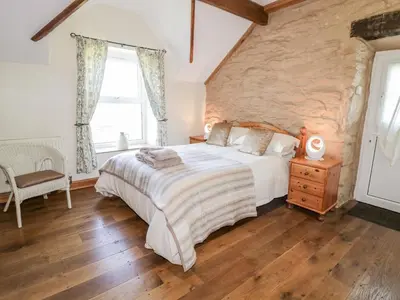a bedroom with a large bed and a stone wall at Tyddyn in Dyffryn