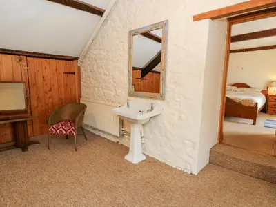 a bathroom with a sink and a mirror and a bed at The Farmhouse in Ciliau-Aeron