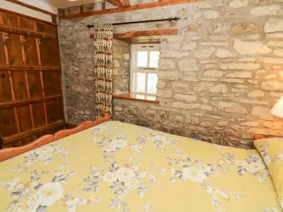 a bedroom with a bed and a stone wall at The Farmhouse in Ciliau-Aeron