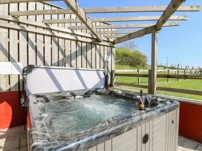 a hot tub on a deck with a pergola at Mill Cottage in Ciliau-Aeron