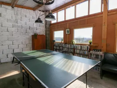 a ping pong table in the middle of a library at Mill Cottage in Ciliau-Aeron