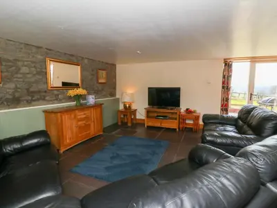 a living room with a leather couch and a television at Mill Cottage in Ciliau-Aeron