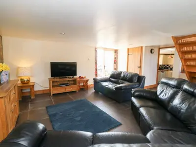 a living room with leather furniture and a flat screen tv at Mill Cottage in Ciliau-Aeron