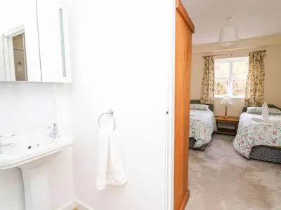a bathroom with a sink and a bed and a mirror at Trout Cottage in Llandrindod Wells