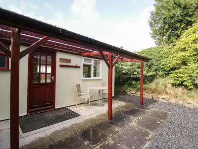 a patio with a table and a house at Trout Cottage in Llandrindod Wells