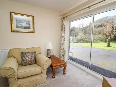 a living room with a chair and a window at Trout Cottage in Llandrindod Wells