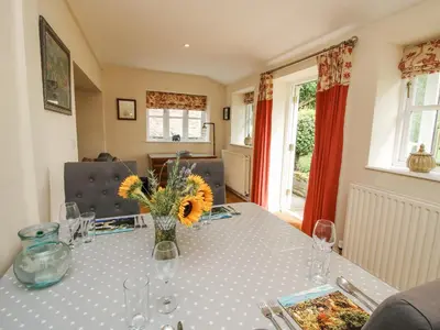 a dining room table with a vase of flowers on it at The Coach House in Ludlow
