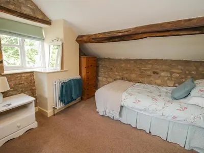 a bedroom with a bed and a stone wall at The Coach House in Ludlow