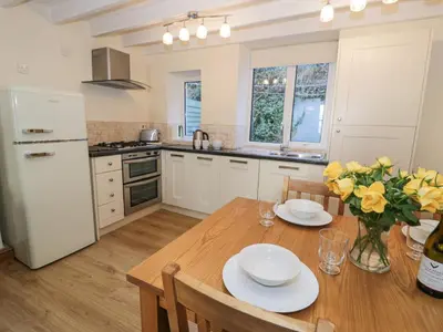 a kitchen with a wooden table with yellow flowers on it at Ty Gwyn in Aberdyfi
