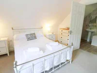 a bedroom with a white bed and a sink at Cariad Cottage in Cilcennin