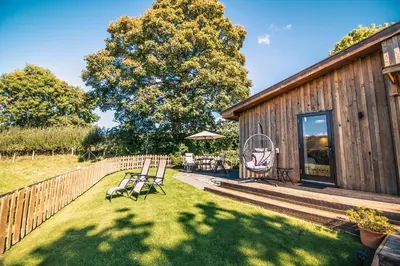 a backyard with a wooden cabin with a table and chairs at Sycamore Lodge in Rhayader