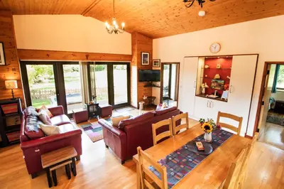 a living room with couches and a table at Sycamore Lodge in Rhayader