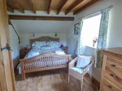 a bedroom with a bed and a chair and a window at The Old Mill in Llanfihangel Rhydithon