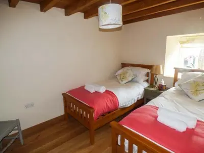 a bedroom with two beds and a red blanket at The Old Mill in Llanfihangel Rhydithon