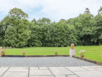 a garden with a lawn and trees in the background at The Old Mill in Llanfihangel Rhydithon