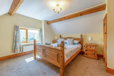 a bedroom with a wooden bed and a window at Maesgwyn in Felindre
