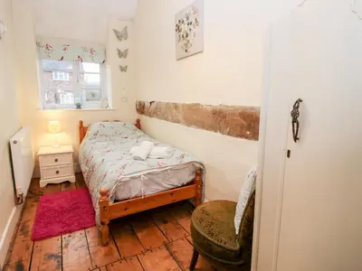 a small bedroom with a bed and a chair at Castle Cottage in Clun