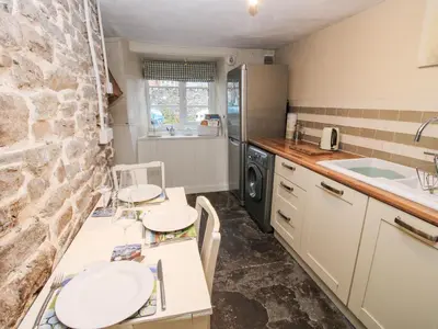 a kitchen with two white counters and a stone wall at Castle Cottage in Clun